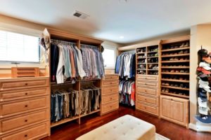 Pretty maple master closet with hat rack, shirts, shoes, bench